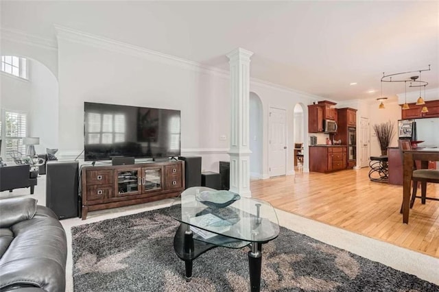 living room featuring crown molding, light hardwood / wood-style flooring, and ornate columns