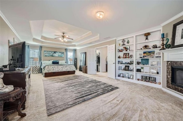 bedroom with ceiling fan, light carpet, a premium fireplace, and a tray ceiling