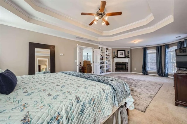 carpeted bedroom featuring crown molding, a raised ceiling, ensuite bathroom, and ceiling fan