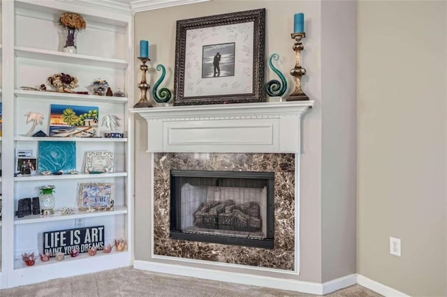 living area featuring ornamental molding, a high end fireplace, and built in shelves