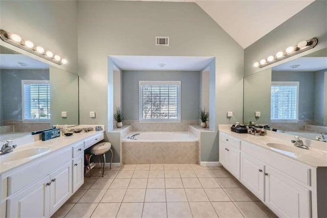 bathroom featuring vanity, tiled bath, and tile patterned flooring