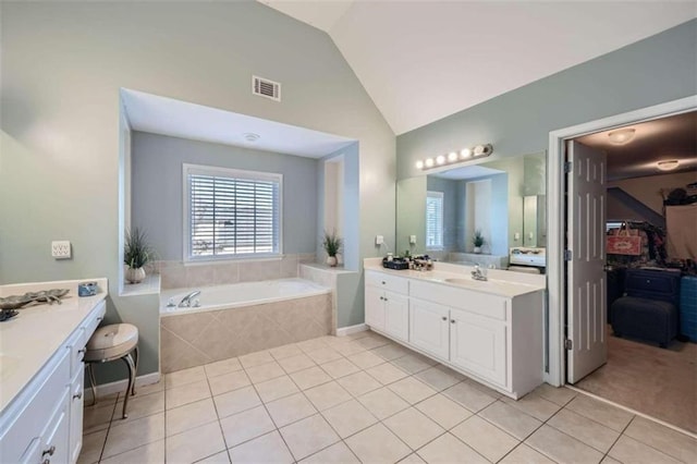 bathroom featuring vanity, a relaxing tiled tub, tile patterned flooring, and vaulted ceiling