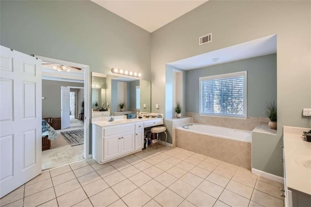 bathroom with vanity, a high ceiling, a relaxing tiled tub, and tile patterned flooring