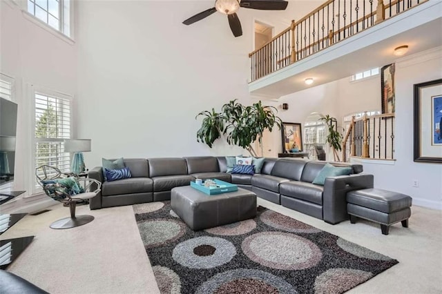 carpeted living room featuring ceiling fan and a high ceiling