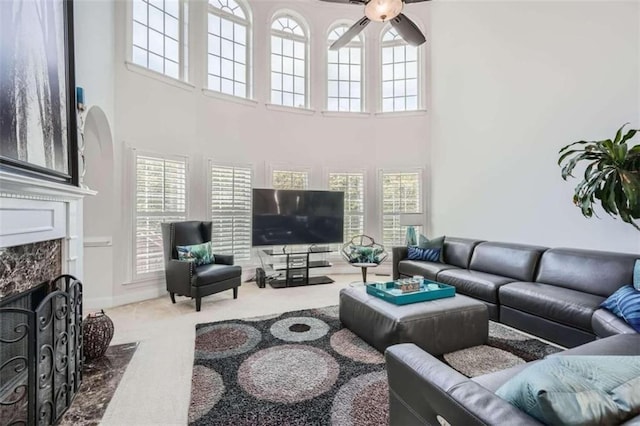 carpeted living room with a towering ceiling, ceiling fan, and a premium fireplace