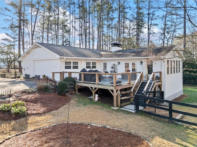 back of house featuring stairs, a wooden deck, a chimney, and fence