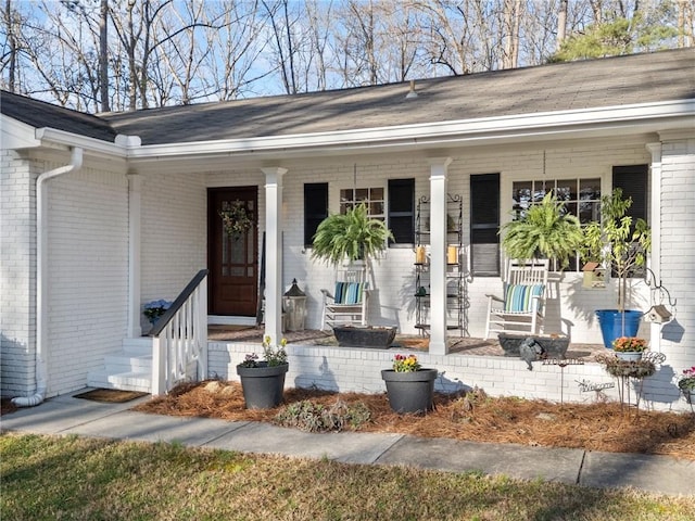 doorway to property with covered porch and brick siding