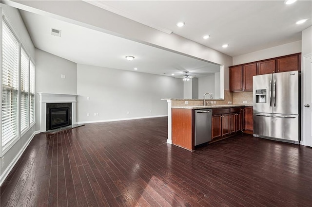 kitchen featuring visible vents, a premium fireplace, a peninsula, dark wood-style flooring, and stainless steel appliances