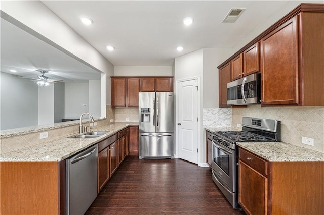 kitchen featuring visible vents, a sink, appliances with stainless steel finishes, light stone countertops, and dark wood-style flooring