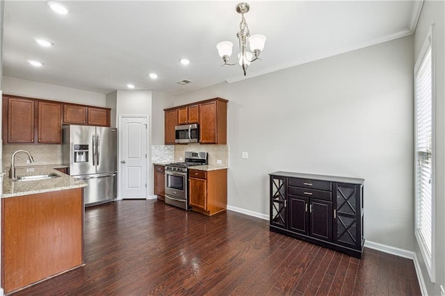 kitchen with baseboards, a sink, stainless steel appliances, dark wood-type flooring, and brown cabinets