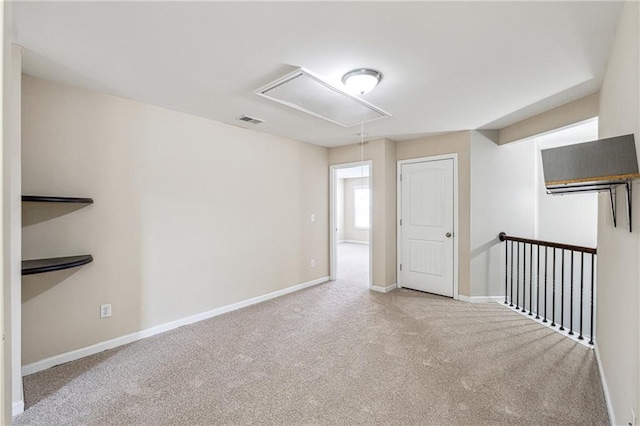 unfurnished room with visible vents, baseboards, carpet, and attic access