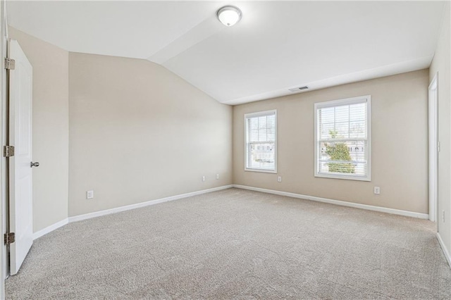 carpeted spare room featuring visible vents, lofted ceiling, and baseboards