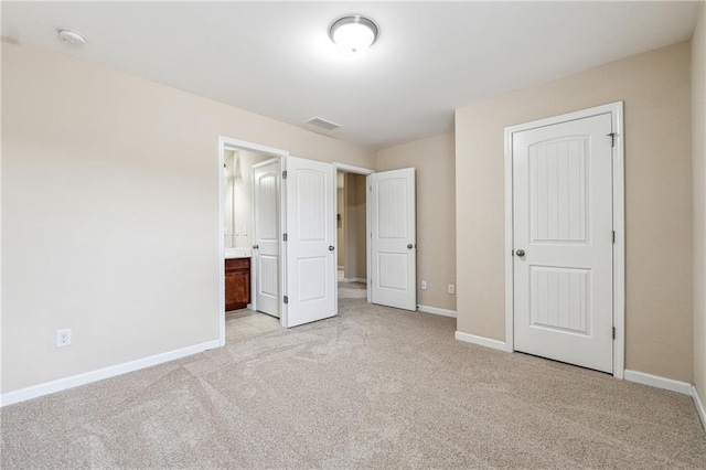 unfurnished bedroom with light carpet, visible vents, ensuite bath, and baseboards