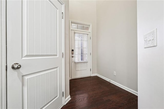 doorway with baseboards and dark wood-style flooring