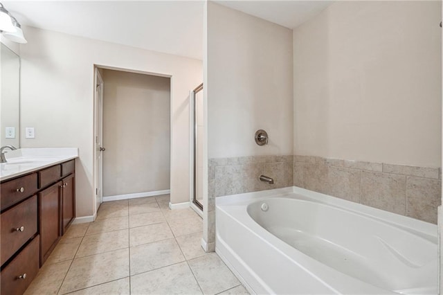 bathroom featuring a garden tub, a stall shower, tile patterned flooring, baseboards, and vanity