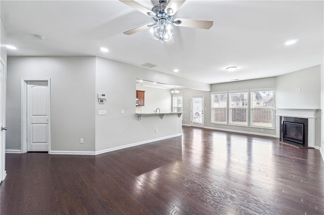 unfurnished living room with a high end fireplace, visible vents, baseboards, and wood finished floors