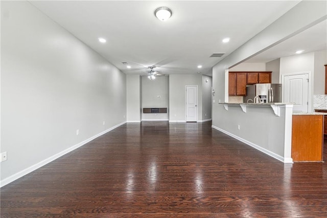 unfurnished living room featuring a ceiling fan, dark wood-style flooring, and baseboards