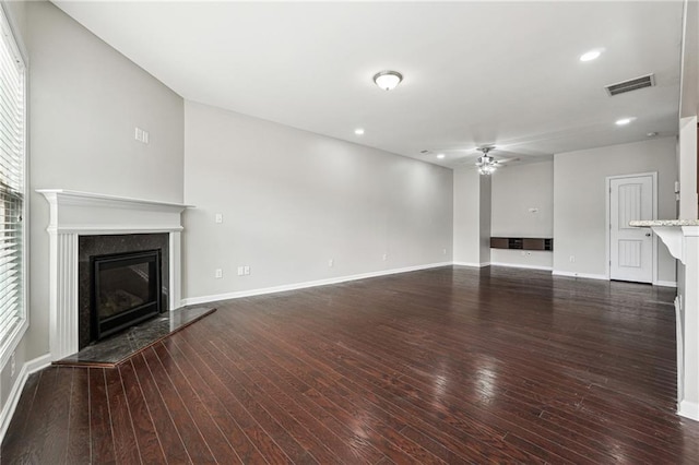 unfurnished living room featuring a high end fireplace, visible vents, baseboards, ceiling fan, and wood-type flooring