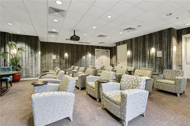 carpeted cinema room with visible vents and a drop ceiling
