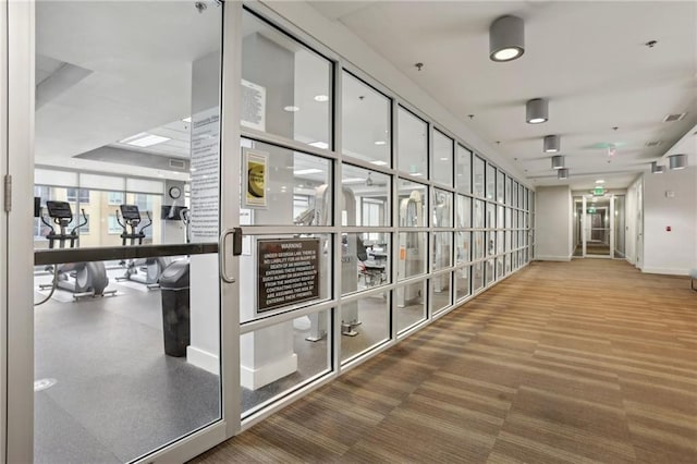 hallway featuring visible vents, carpet, and baseboards