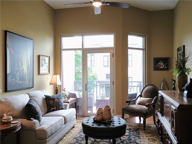 living area with light wood-type flooring, a ceiling fan, and plenty of natural light