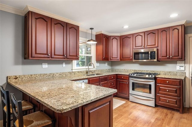 kitchen with kitchen peninsula, light stone counters, stainless steel appliances, sink, and pendant lighting