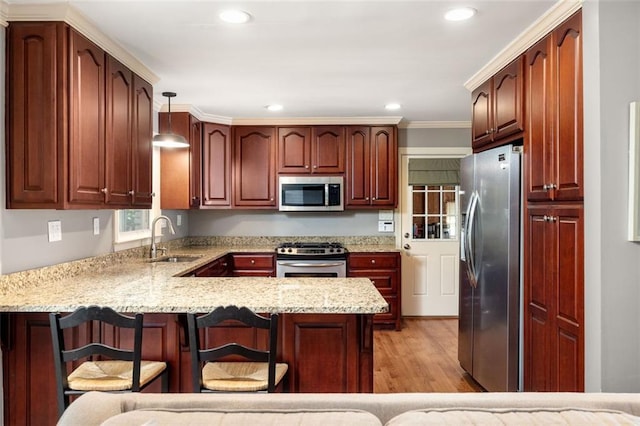 kitchen featuring sink, stainless steel appliances, hanging light fixtures, kitchen peninsula, and a breakfast bar area