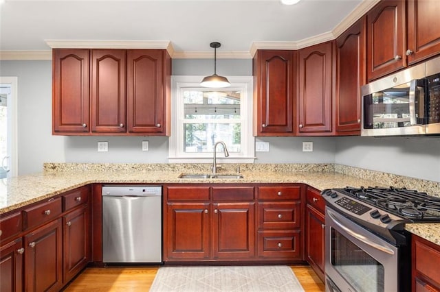 kitchen with light stone countertops, appliances with stainless steel finishes, ornamental molding, sink, and decorative light fixtures