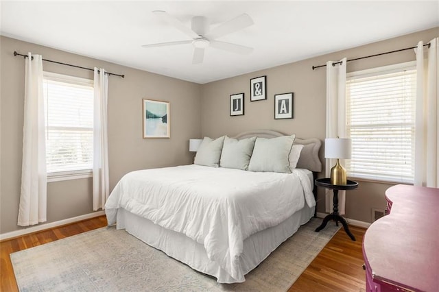 bedroom featuring multiple windows, ceiling fan, and hardwood / wood-style flooring