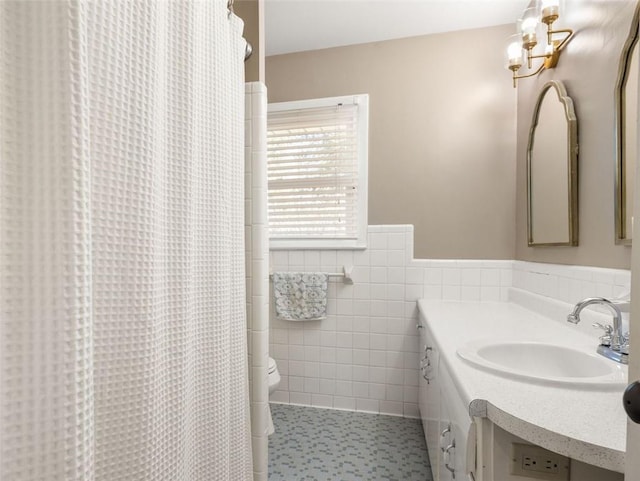 bathroom featuring tile patterned floors, vanity, toilet, and tile walls