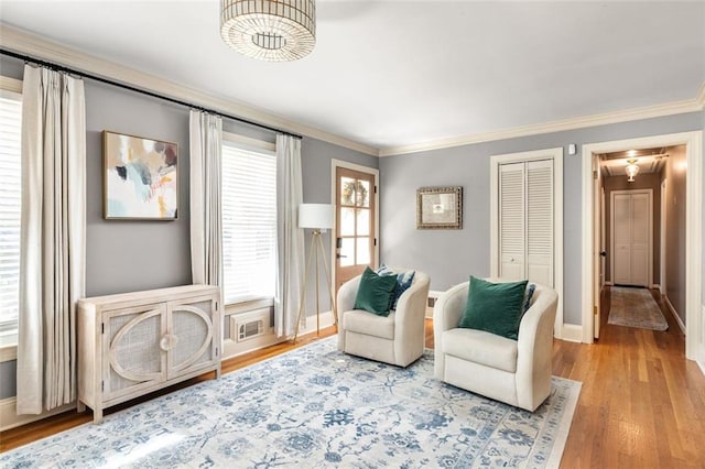 living area with a wealth of natural light, wood-type flooring, and ornamental molding