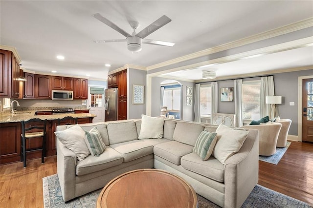 living room featuring light hardwood / wood-style flooring, ceiling fan, crown molding, and sink