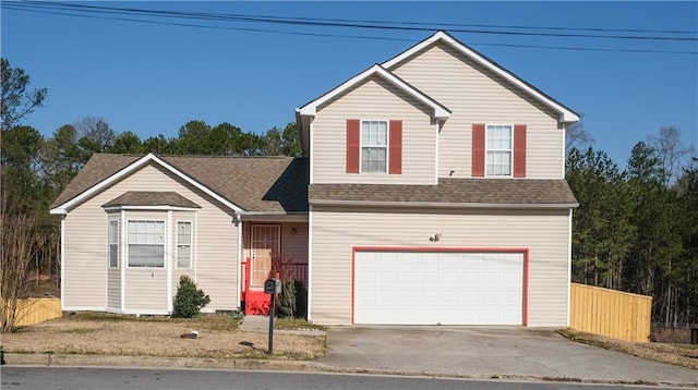 traditional-style house featuring an attached garage, fence, concrete driveway, and roof with shingles