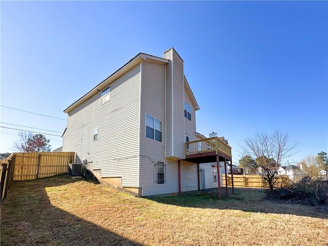 rear view of house featuring central AC unit, a lawn, a chimney, fence, and a wooden deck