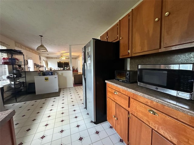 5546 Wellborn Creek Dr, Lithonia, GA 30058 - kitchen with appliances with stainless steel finishes, brown cabinetry, a textured ceiling, light floors, and a ceiling fan