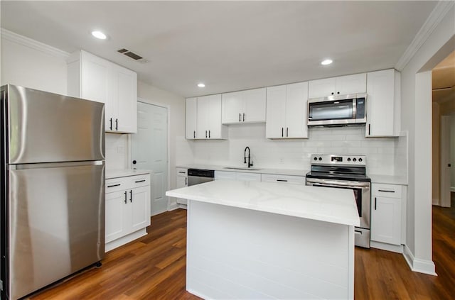 kitchen with a sink, appliances with stainless steel finishes, ornamental molding, and tasteful backsplash