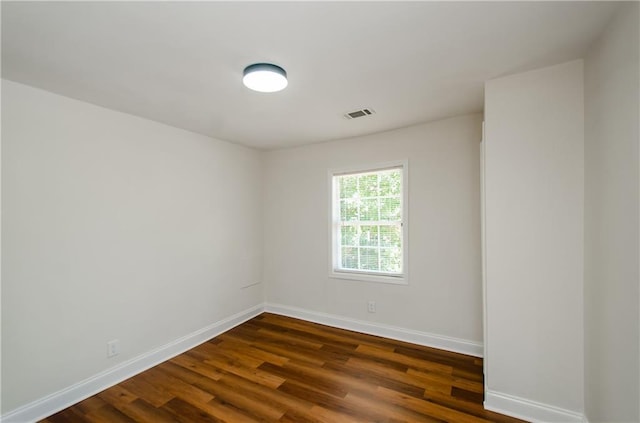 spare room with baseboards, dark wood-style floors, and visible vents