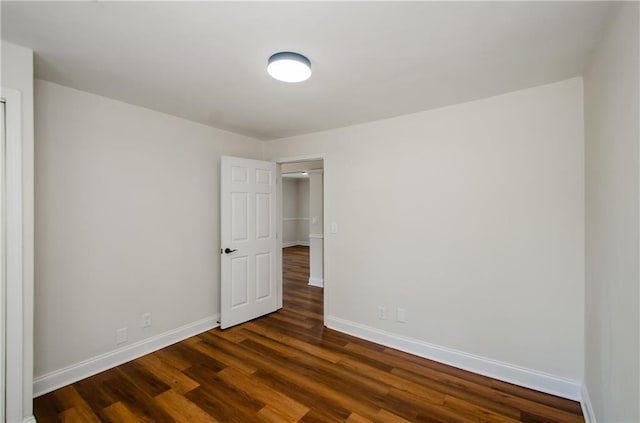 empty room featuring baseboards and dark wood finished floors