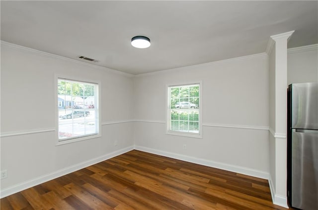 empty room with visible vents, ornamental molding, dark wood finished floors, and a healthy amount of sunlight