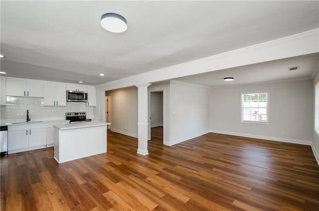 kitchen with backsplash, white cabinetry, ornamental molding, dark wood-type flooring, and stainless steel appliances