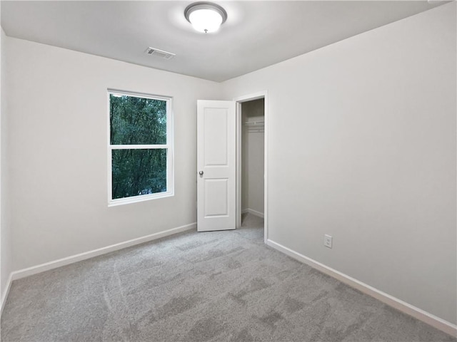 unfurnished bedroom with light colored carpet and a closet