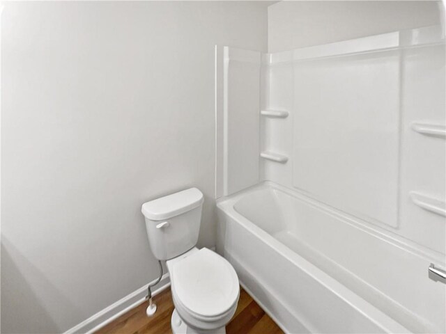 bathroom featuring wood-type flooring, bathing tub / shower combination, and toilet