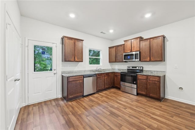 4001 Avalon Rd SW, Atlanta, GA 30331 - kitchen featuring light stone counters, appliances with stainless steel finishes, a sink, light wood-type flooring, and visible vents