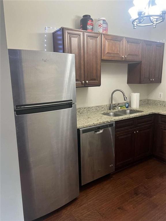 kitchen with hanging light fixtures, sink, dark wood-type flooring, stainless steel appliances, and an inviting chandelier