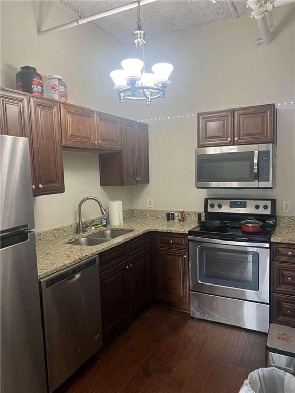 kitchen with appliances with stainless steel finishes, hanging light fixtures, dark hardwood / wood-style flooring, sink, and a notable chandelier