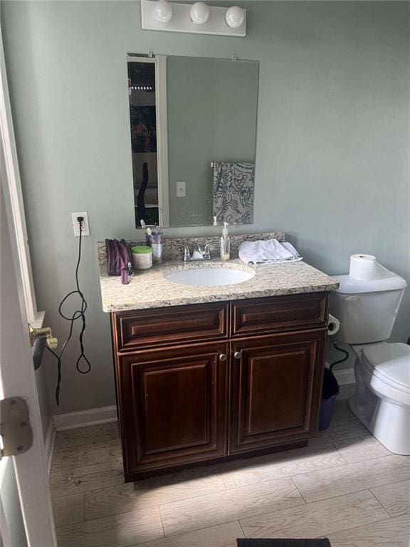 bathroom featuring wood-type flooring, vanity, and toilet