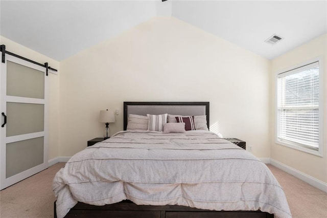 carpeted bedroom featuring a barn door and vaulted ceiling