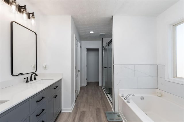 bathroom with wood-type flooring, shower with separate bathtub, a textured ceiling, and vanity