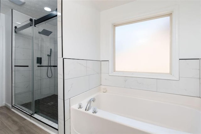 bathroom featuring hardwood / wood-style flooring, shower with separate bathtub, and a textured ceiling