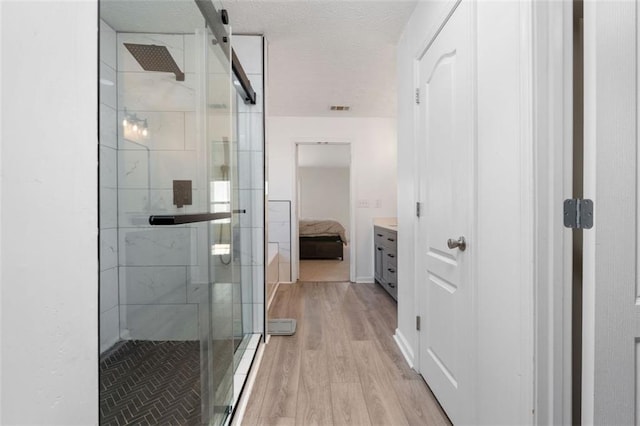 bathroom featuring vanity, hardwood / wood-style floors, a textured ceiling, and walk in shower